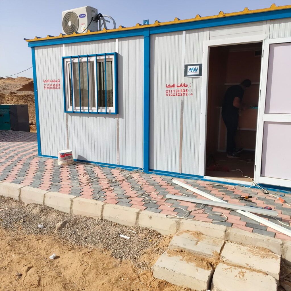 كرفان ساندوتش بانل بتكييف ونافذة بحماية حديد وباب مفتوح على أرض مبلطة