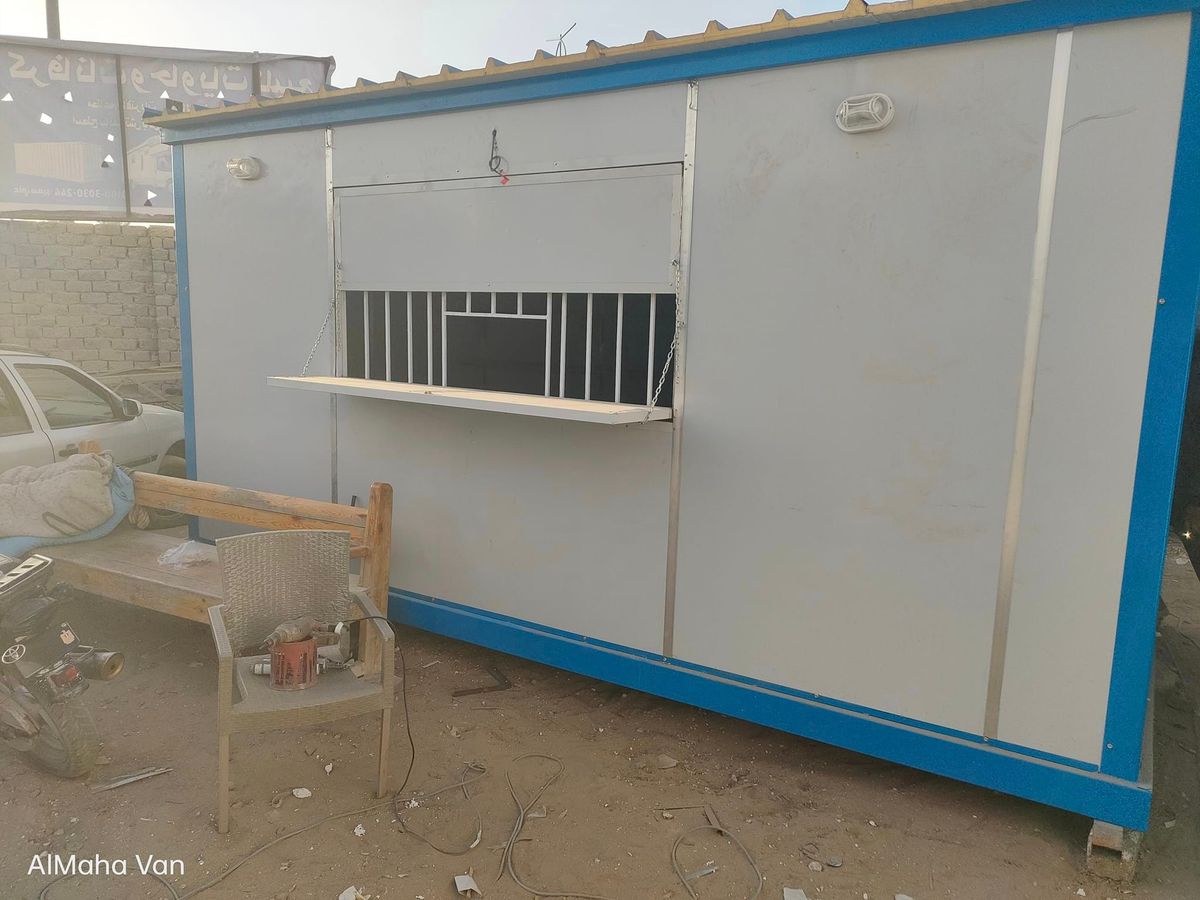كرفان ساندوتش بانل بشباك بيع بحماية حديد ورف خارجي في ساحة رملية