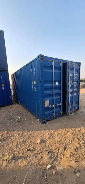 حاوية شحن 20 قدم زرقاء مستعملة بأبوابها المغلقة على أرض ترابية في ساحة