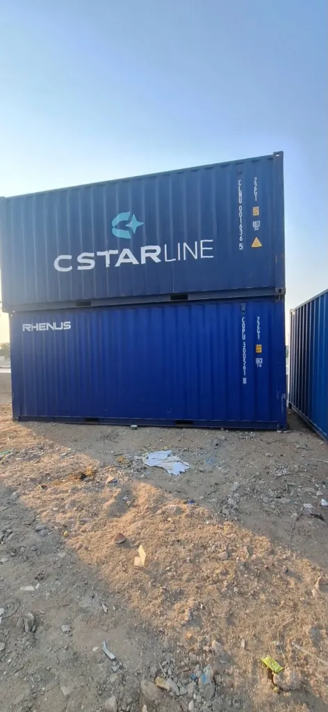 حاويتا شحن 20 قدم زرقاء مرصوصتان فوق بعضهما في ساحة ترابية