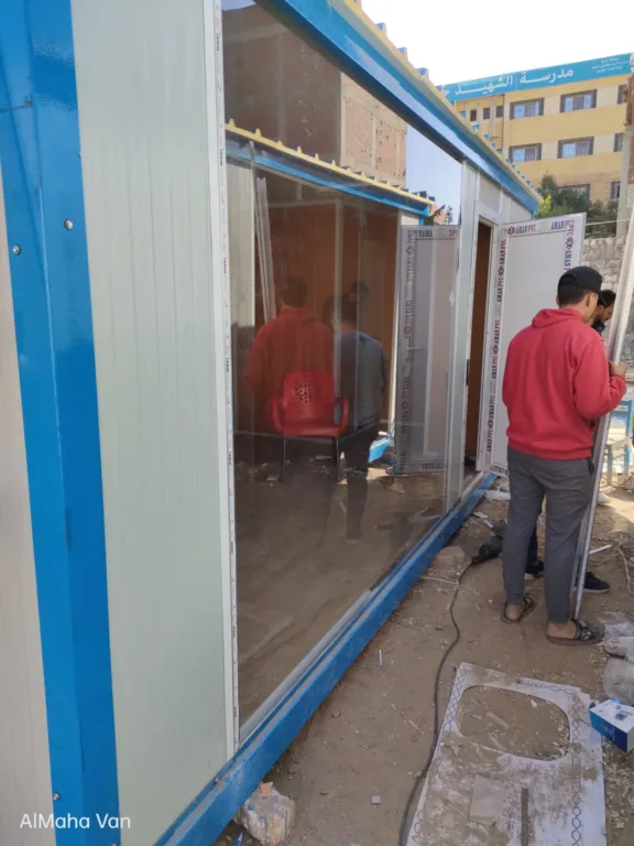 فنيون يركّبون واجهة سكريت زجاجية لكرفان في الموقع