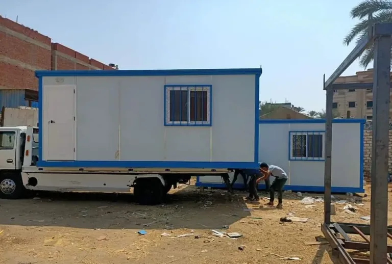 كرفان ساندوتش بانل بنافذة بحماية حديد محمّل على شاحنة وبجواره كرفان آخر